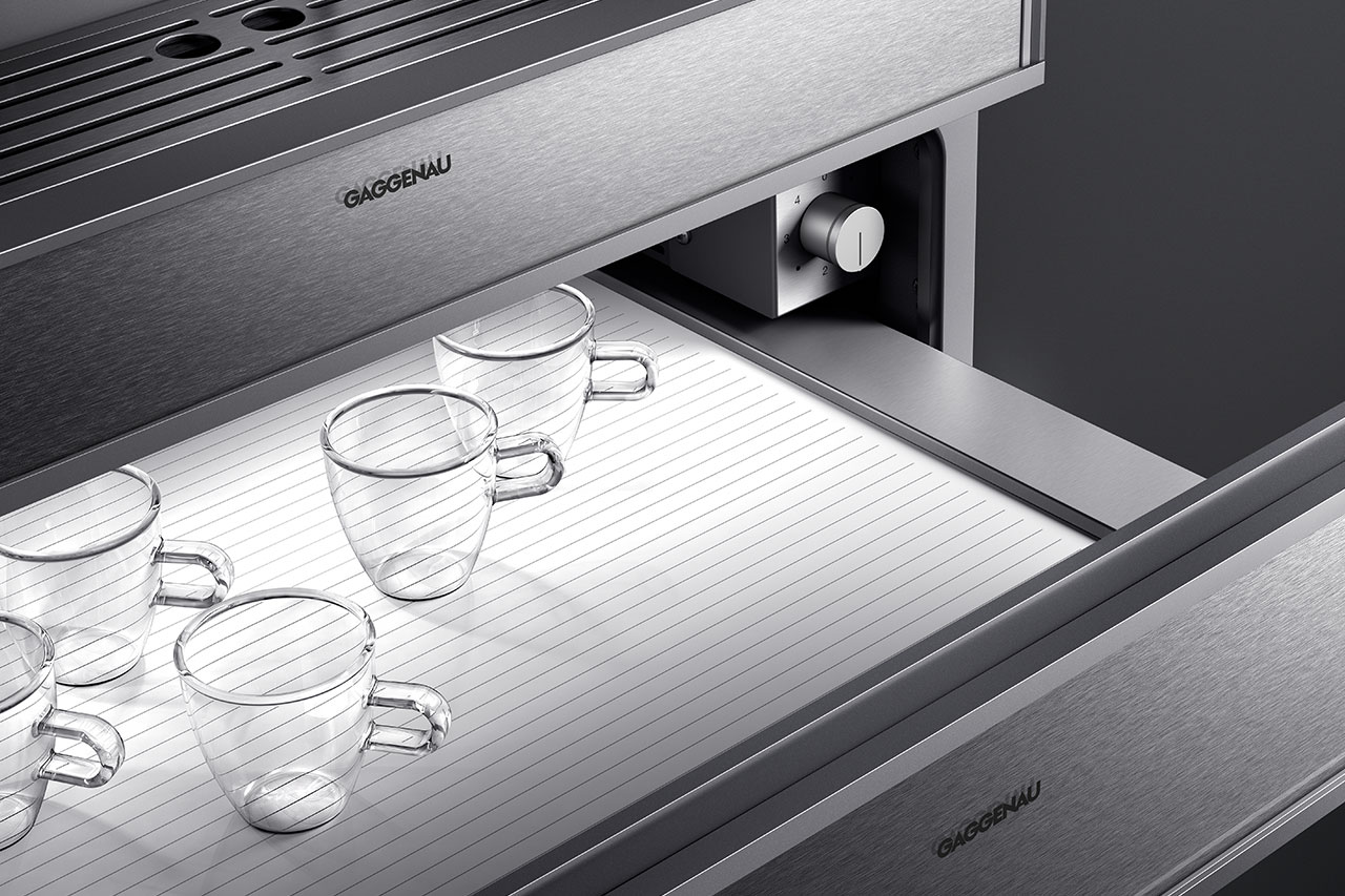 Postproduktion und High-End-Bildbearbeitung – Visual: geöffnete, beleuchtete Gaggenau Wärmeschublade mit gläsernen Espressotassen darin