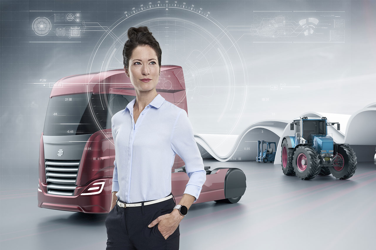 Key Visual für „Nutzfahrzeuge“, EDAG Production Solutions: Frau, Blick in die Ferne nach oben rechts, steht vor angedeutetem futuristischen LKW-Zugteil, Traktor, Gabelstapler, technische Zeichnungen im Hintergrund